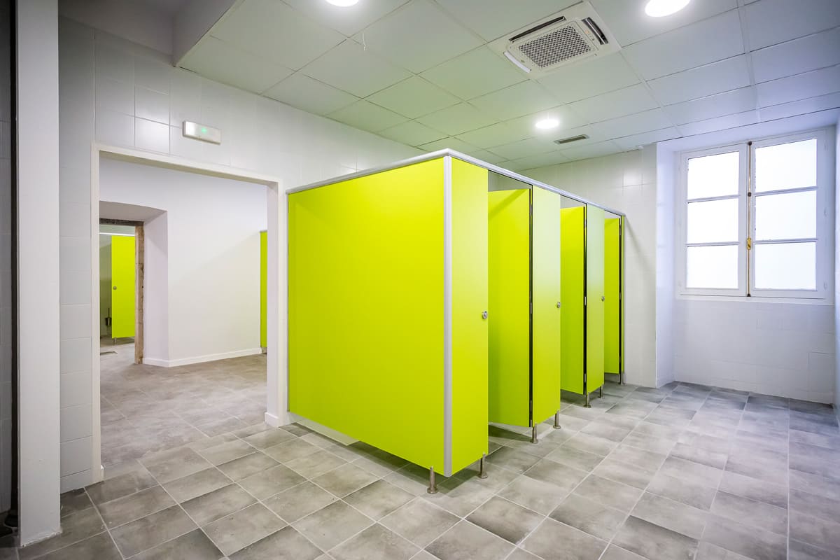 Baños del Centro de Formación Ocupacional en Avilés con cubículos verdes y diseño moderno.