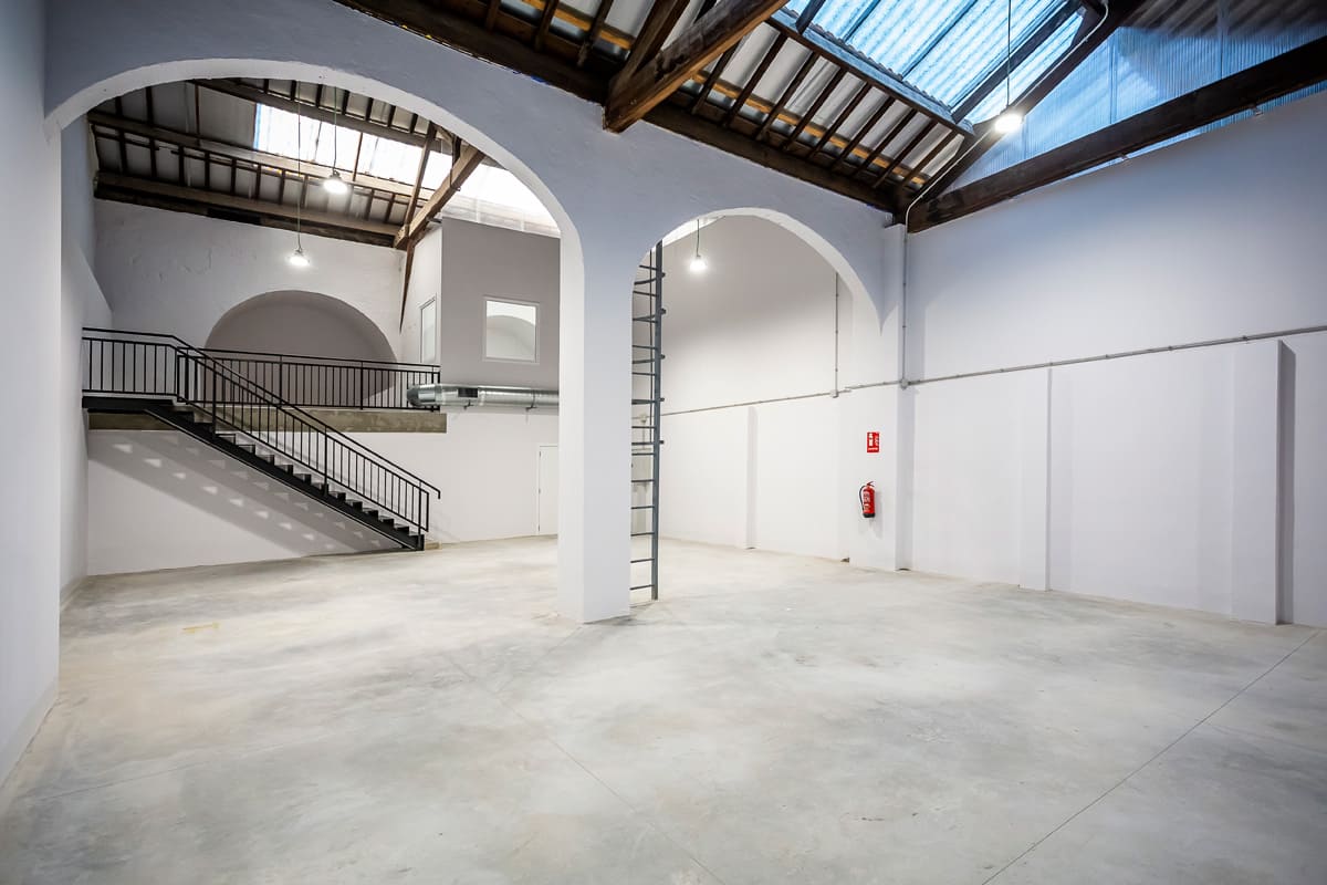 Interior del Centro de Formación Ocupacional en Avilés con espacio abierto, arcos y escalera moderna.